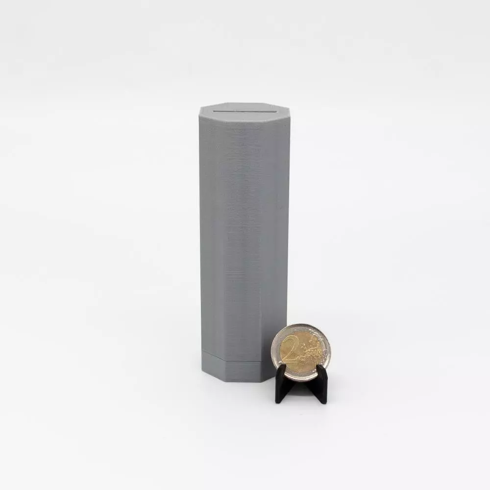Geschlossene silberne zylindrische PAZL Box Rhea neben 2-Euro-Münze – Größenvergleich, Box deutlich höher als Kronos